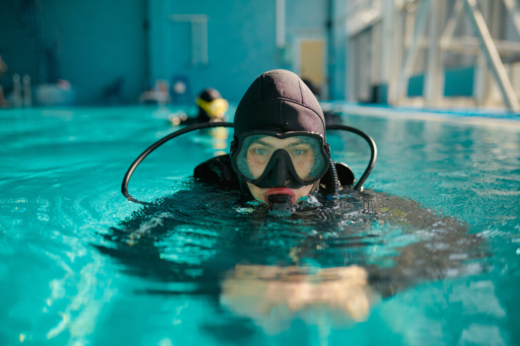 Male diver in scuba gear and mask poses in pool