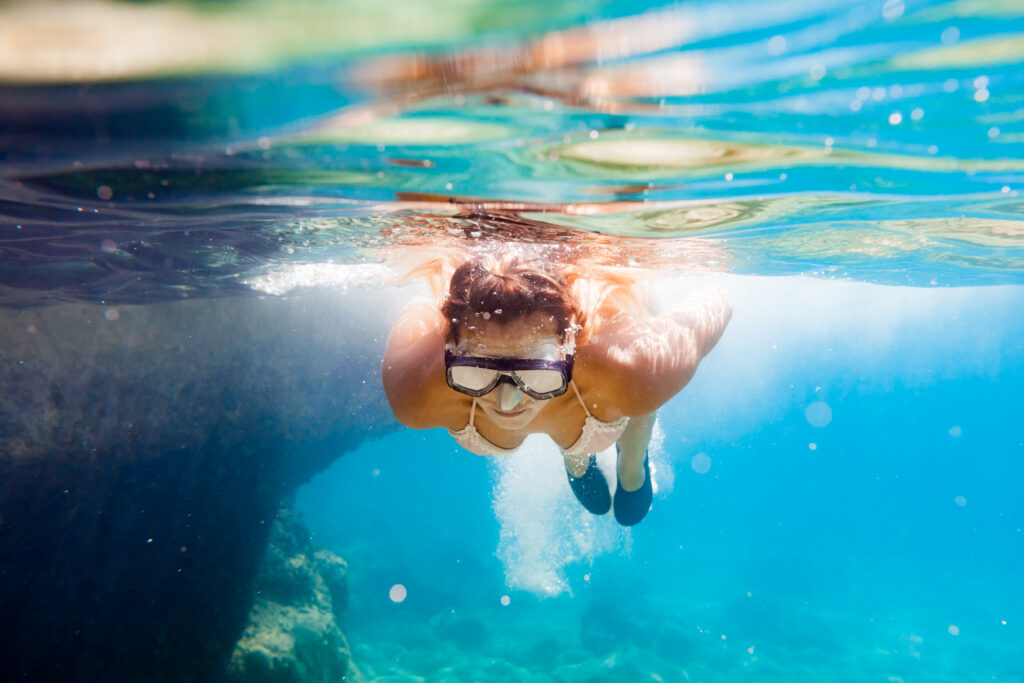 Snorkeling in the tropical sea, woman with mask diving underwater